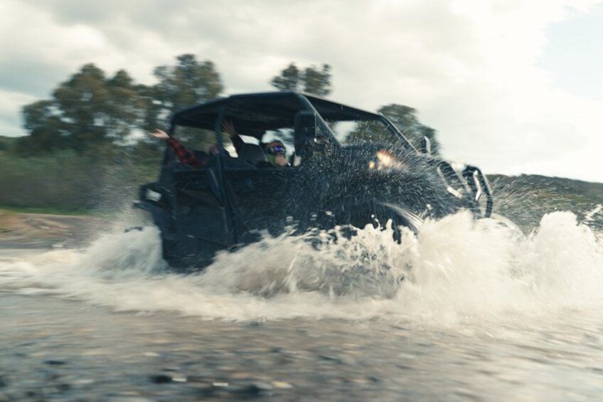 A vehicle driving through water, splashing as it moves forward. 5