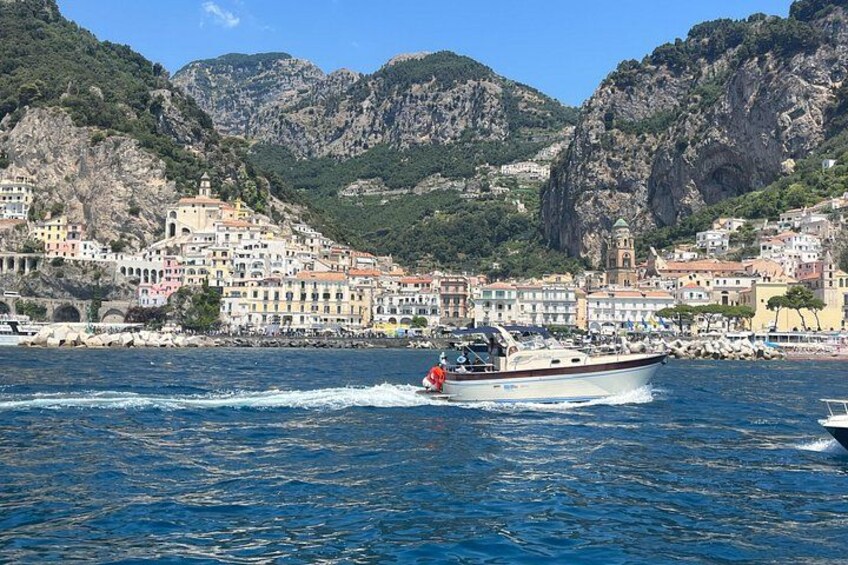 A coastal town with colorful buildings, a boat with a person on the water, and mountains in the background. 4