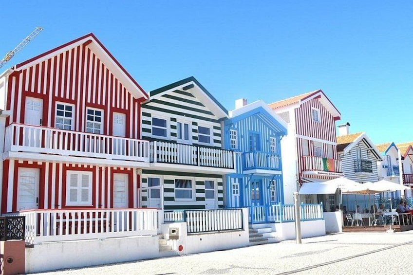 Colorful wooden houses with balconies, a clear blue sky, and a gravel path. 1