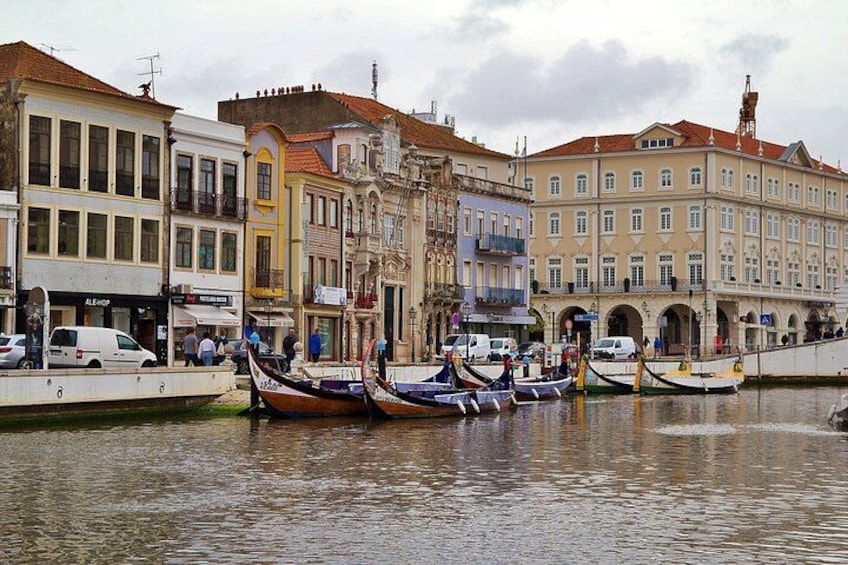 A riverside with boats docked, historic buildings, and a bridge. 2