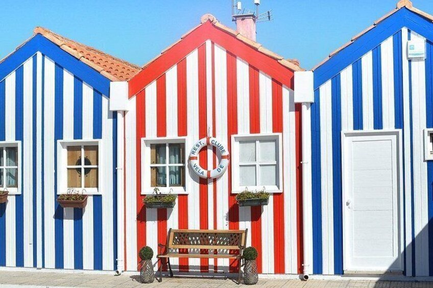 A row of colorful striped buildings with a bench in front. 4