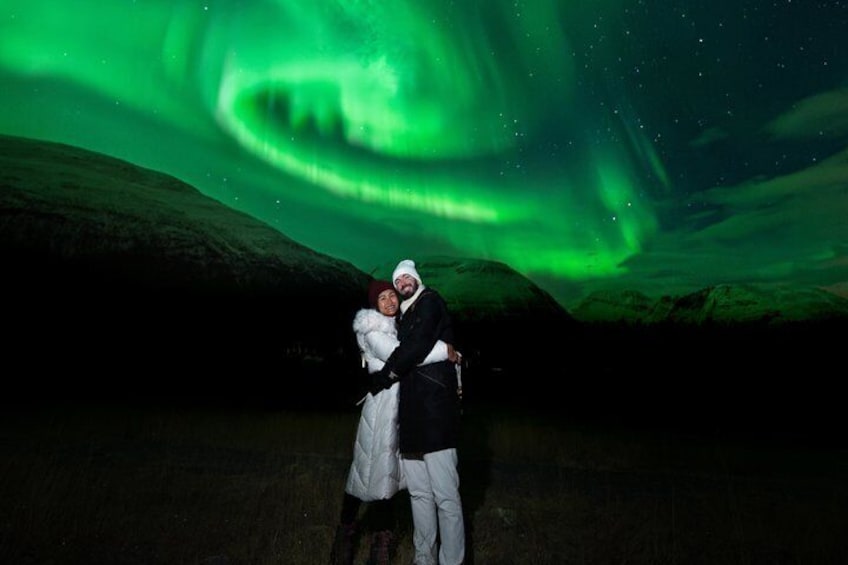 A couple embracing under a green aurora display. 3