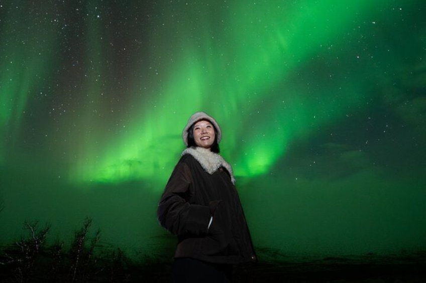 A person standing under a green aurora display. 2