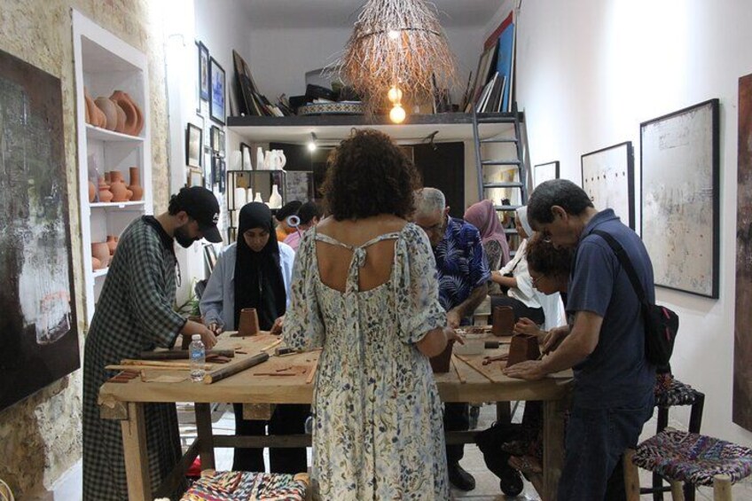 Un grupo de personas trabajando en cerámica en un taller lleno de piezas y herramientas de alfarería. 2