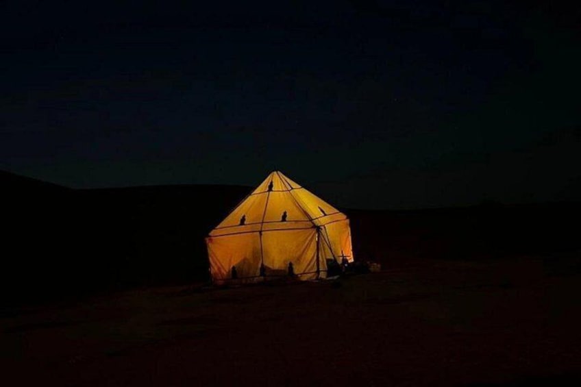 Une tente illuminée la nuit, dans un paysage désertique. 3