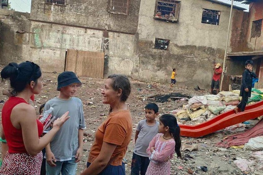 Een groep mensen staat in een rommelig buitengebied met afval en een rode glijbaan. 3