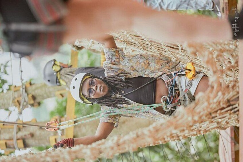 A person on a zip line with a helmet, harness, and safety gear. 5