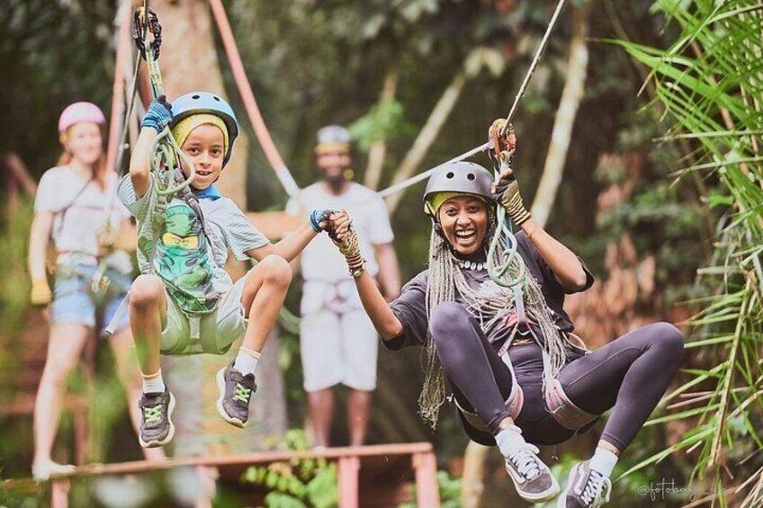 People on a zip line in a forested area. 3