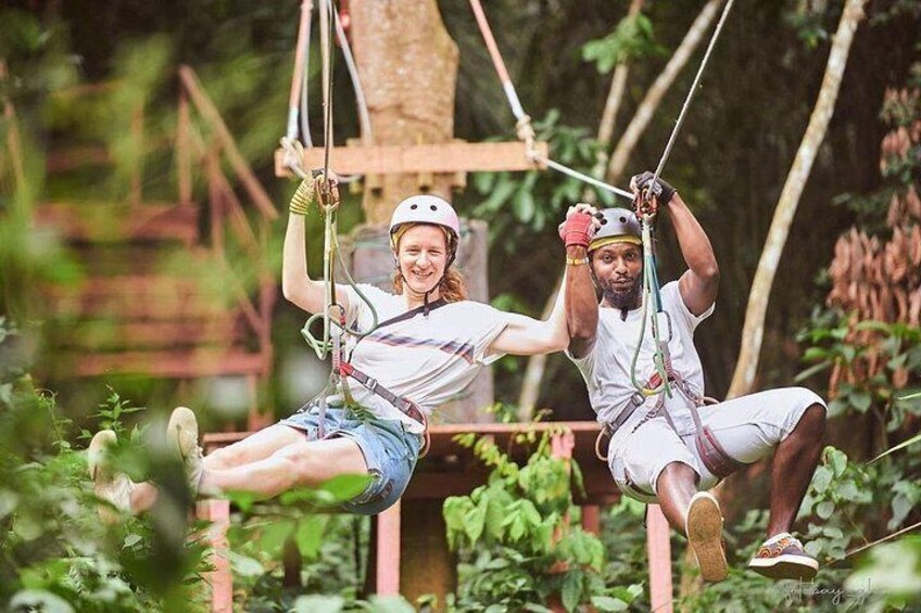 Two people on a zip line in a forested area. 2