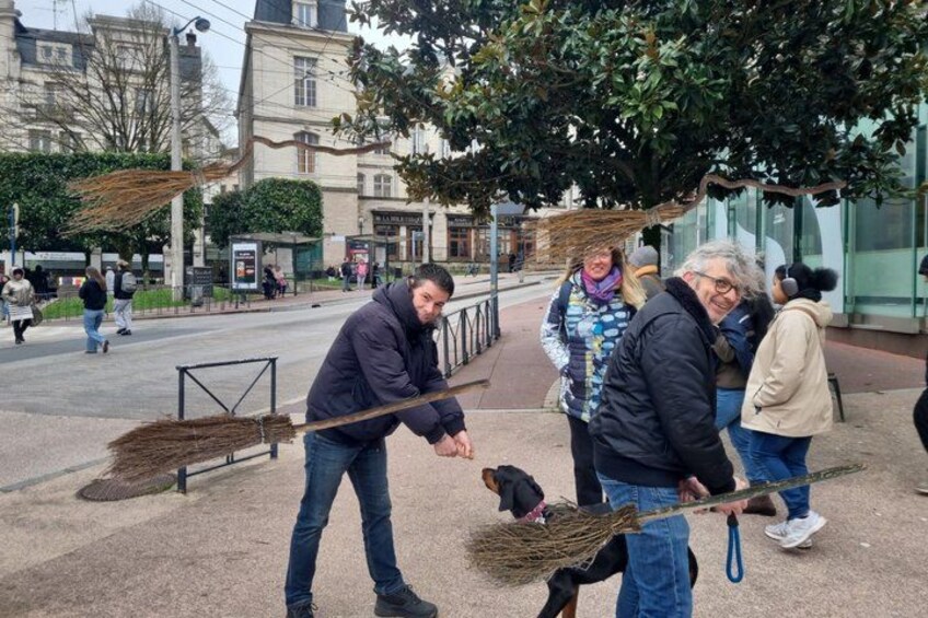 A person sweeping the street with a broom, a dog, and several pedestrians in an urban setting. 4