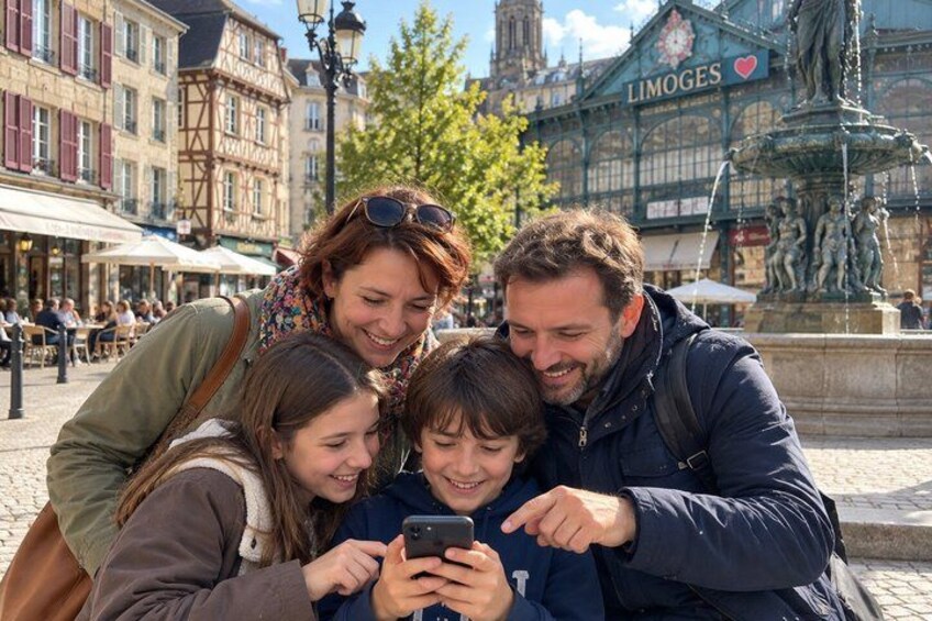 A family of four looking at a smartphone in a European town square with historic buildings and a statue in the background. 5