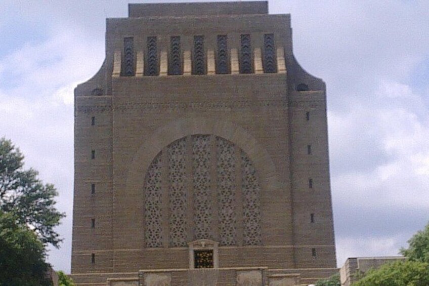 A tall brick tower with a large arched window and decorative patterns. 4