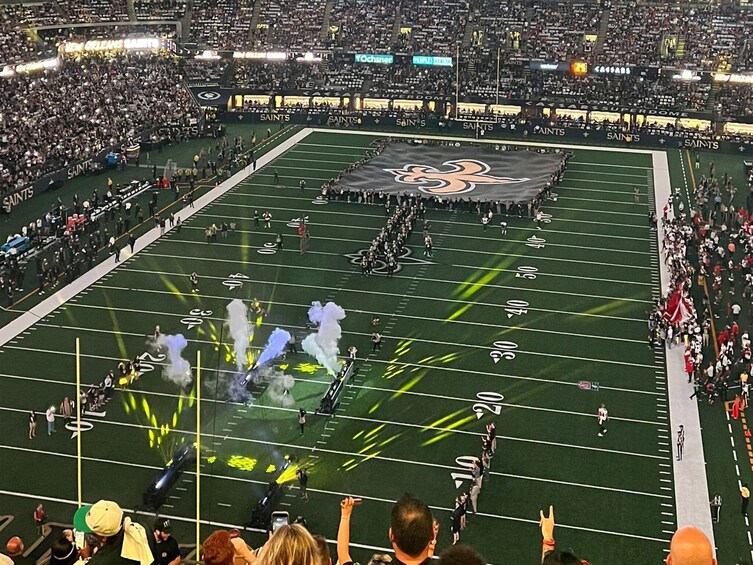 A football stadium with a marching band performing on the field. 1
