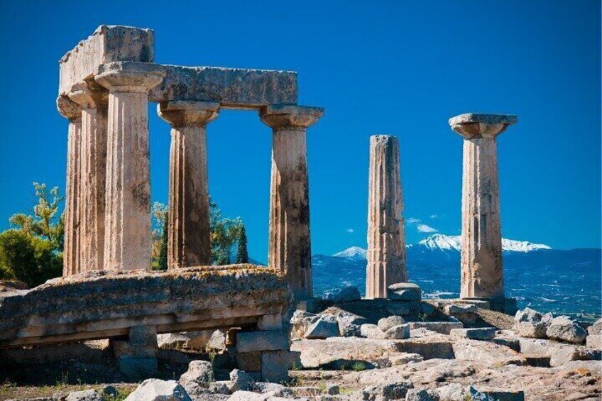 Ancient ruins with columns, a stone platform, and a mountainous backdrop. 2