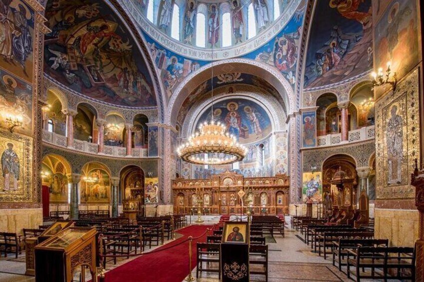An ornate church interior with high ceilings, detailed frescoes, and a central altar. 3