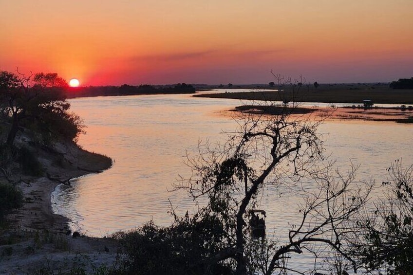 A sunset over a river with a silhouette of a tree in the foreground. 3