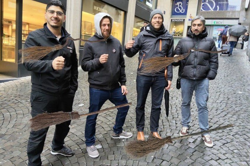 Fyra personer som håller i sopkvastar på en kullerstensgata. 5