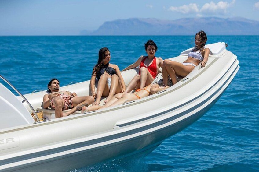 A group of people on a motorboat in the water with mountains in the background. 3