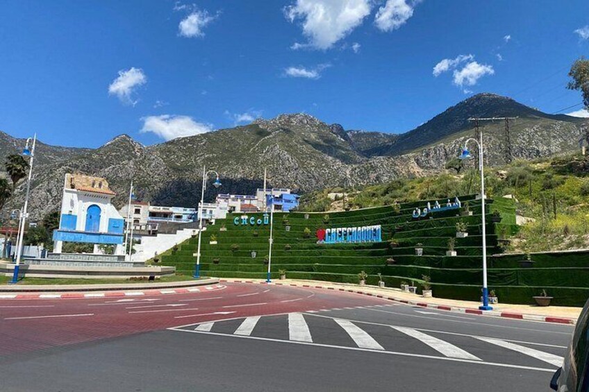 Ett övergångsställe, en blå byggnad, terrasserade gröna fält och berg i bakgrunden. 1