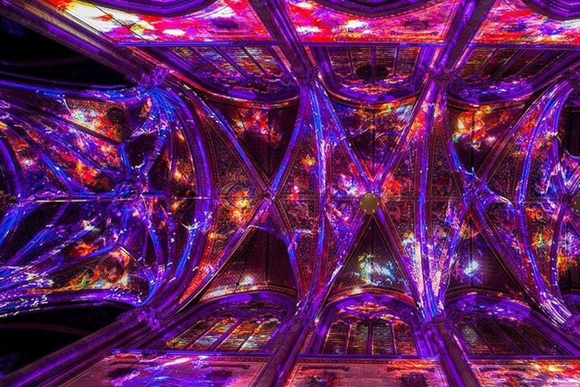 Une structure architecturale complexe et illuminée, caractérisée par des poutres qui se croisent et des surfaces réfléchissantes. 5