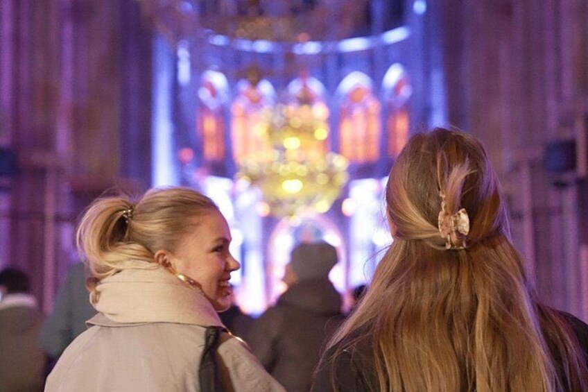 Two people walking towards a brightly lit building with Gothic architecture. 4