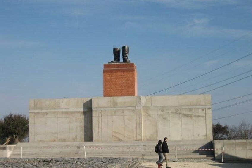 Ett monument av betong med en bas av tegel och två statyer ovanpå. 2