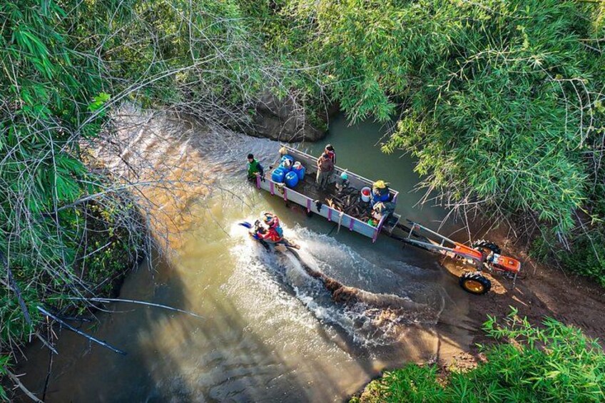 A river with a boat carrying people and equipment, surrounded by dense greenery. 3