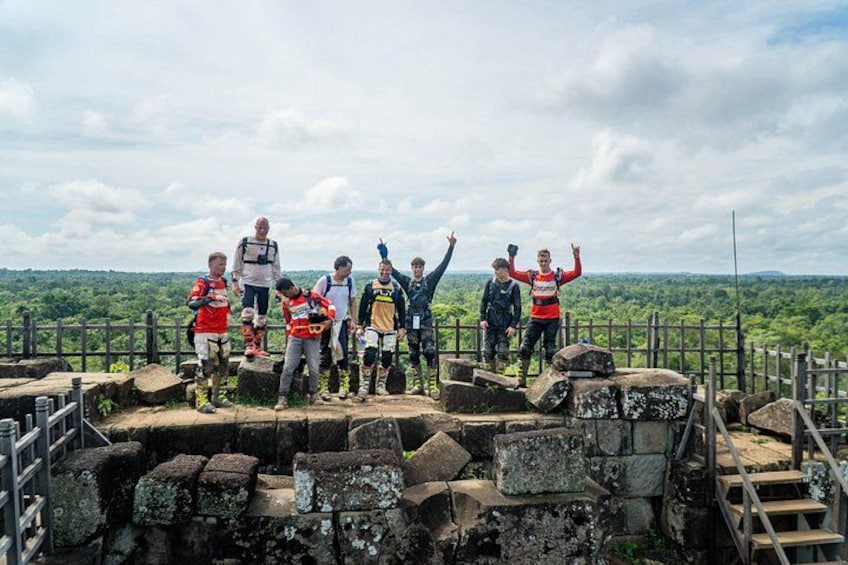 A group of people standing on a stone platform with a forested landscape in the background. 5