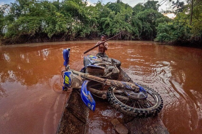 A person paddling a canoe through a muddy river surrounded by dense greenery. 4