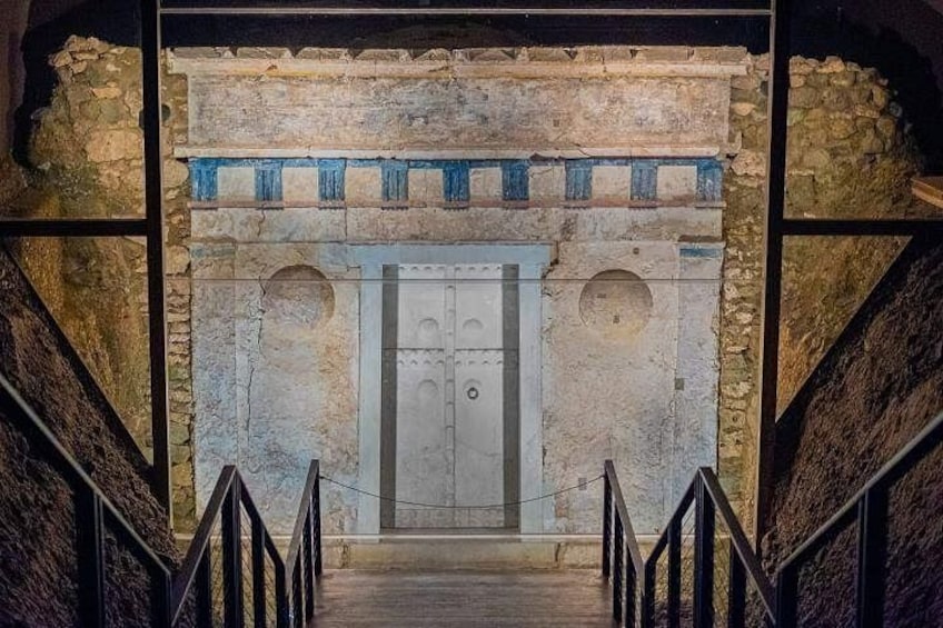 A stone staircase leading to a door with a blue and white design, surrounded by stone walls. 3