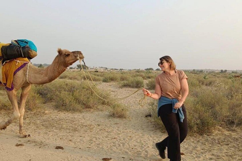 A person leading a camel in a desert landscape. 1