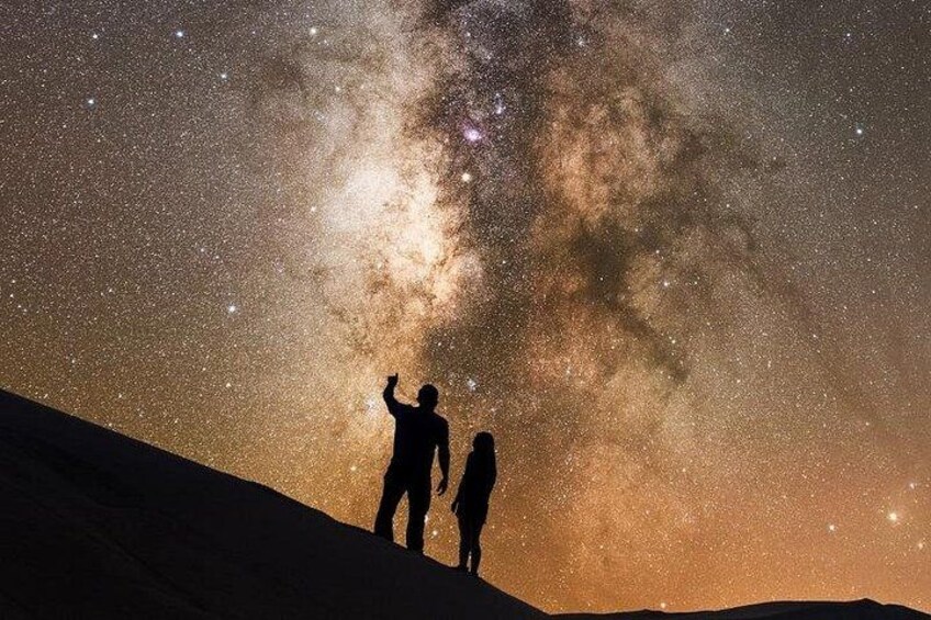 Two people standing on a hill under a starry night sky with the Milky Way visible. 5
