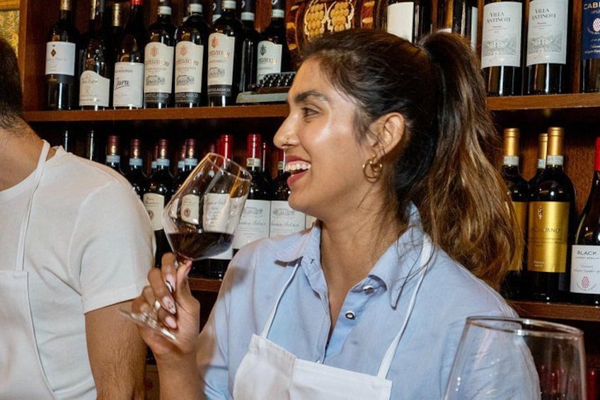 A person holding a wine glass in a bar with shelves of wine bottles. 2