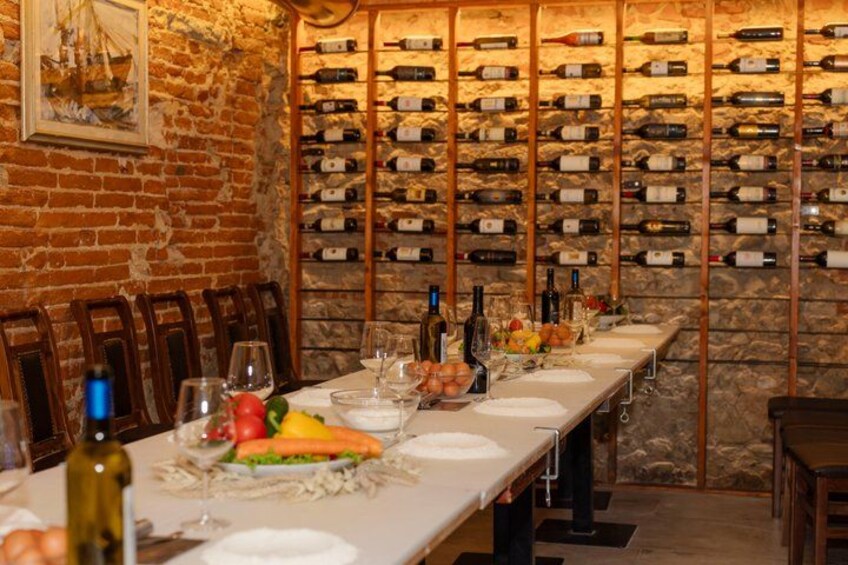 A long dining table set in a rustic room with a brick wall and a wine rack. 2