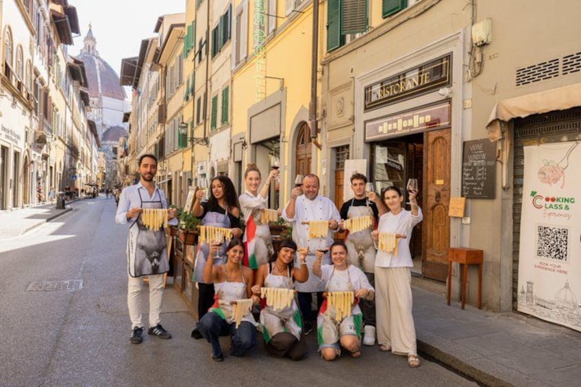 A group of people posing in front of a restaurant on a street. 1