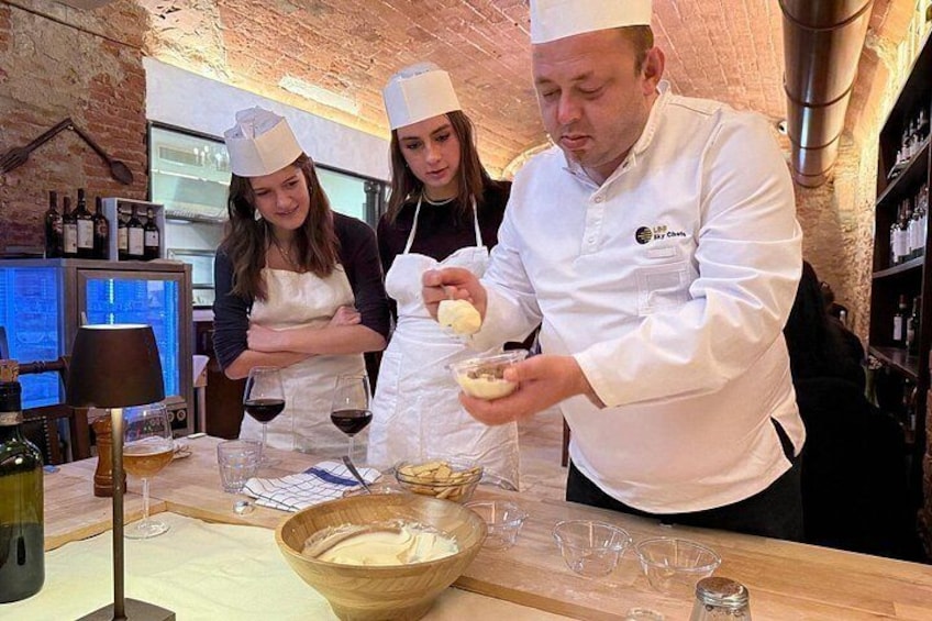 Cuochi che preparano cibo in una cucina con bottiglie e bicchieri di vino sul bancone. 3