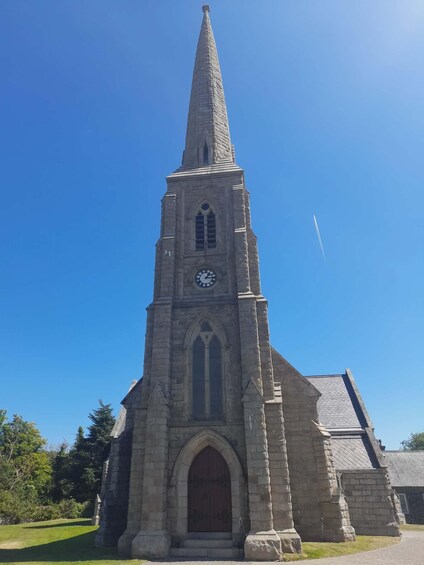 A tall stone church with a pointed steeple and a clock. 2