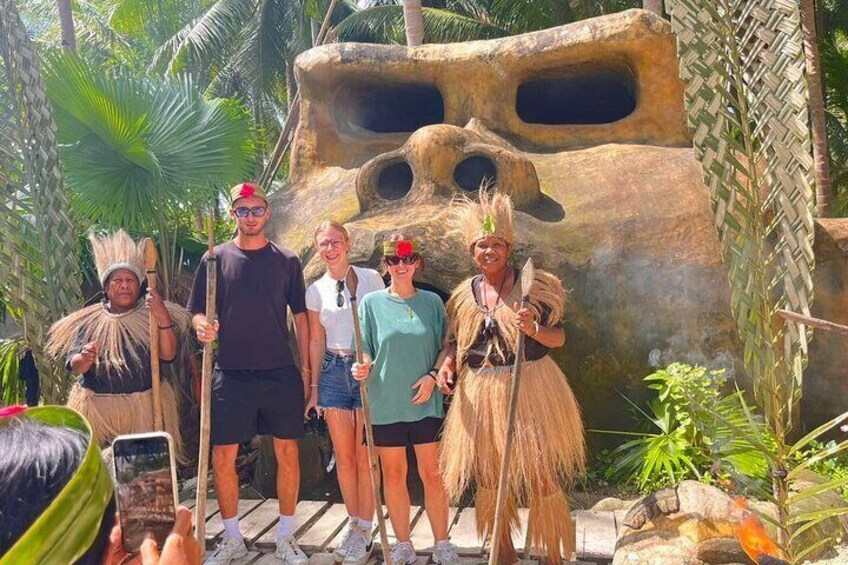 Un groupe de personnes vêtues de costumes traditionnels se tient devant une grande formation rocheuse percée de trous. 1