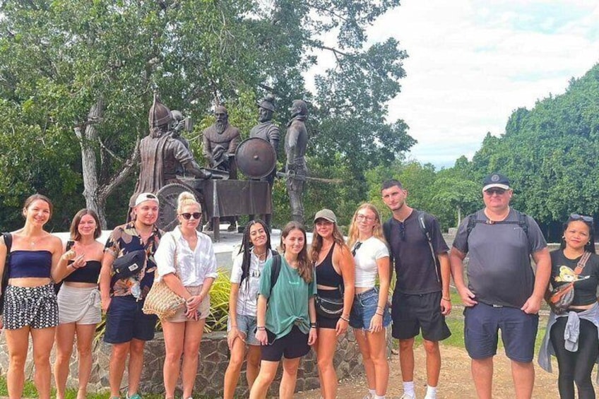 A group of people posing in front of a statue. 1