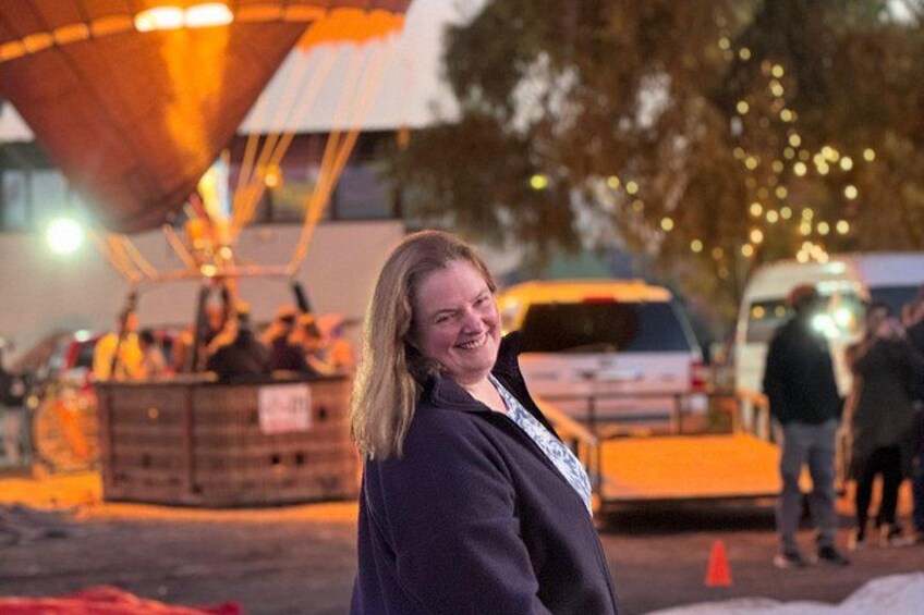 A person standing in front of a large, illuminated structure with a crowd in the background. 3