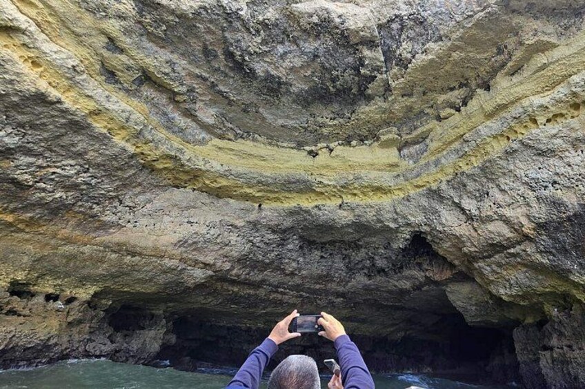 En person fotograferer en klippeformation med lagdelt sediment. 4