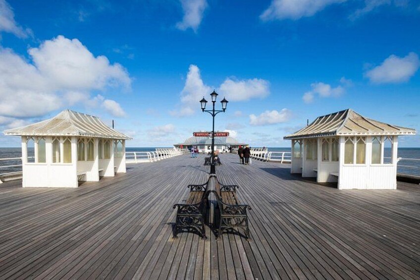 A wooden pier with gazebos, a lamppost, and a distant building. 4