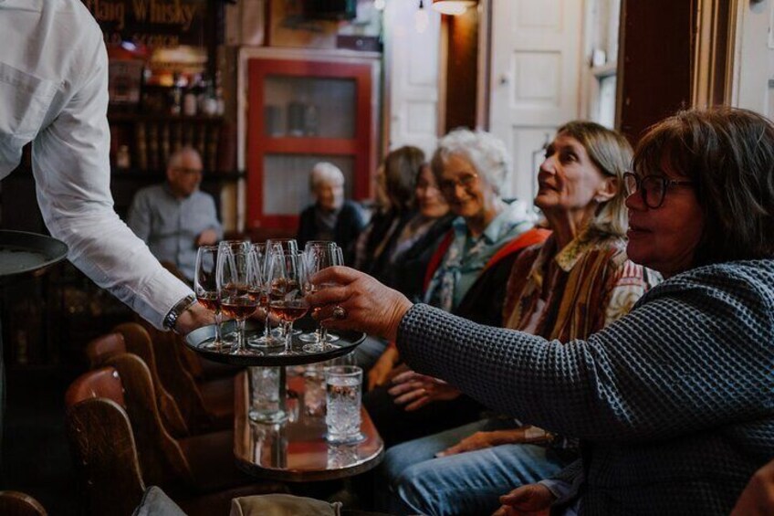 A group of people toasting with wine glasses in a bar setting. 1