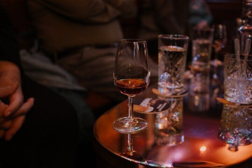 A glass of red wine on a table with other glasses and a bottle. 5