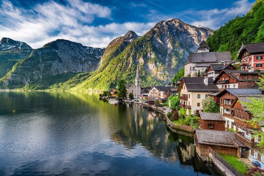 A calm lake with a mountain backdrop, traditional houses, and a church. 3
