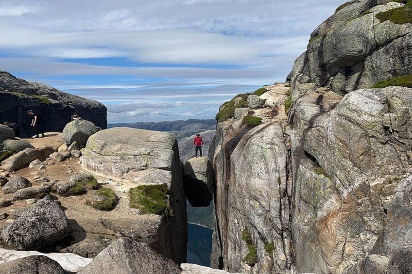 A rocky landscape with a person in red standing on a ledge. 5