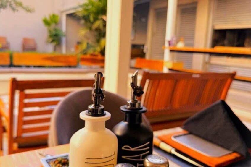 A table with a white and black bottle, a black bag, and a smartphone on a wooden table in a cafe. 3