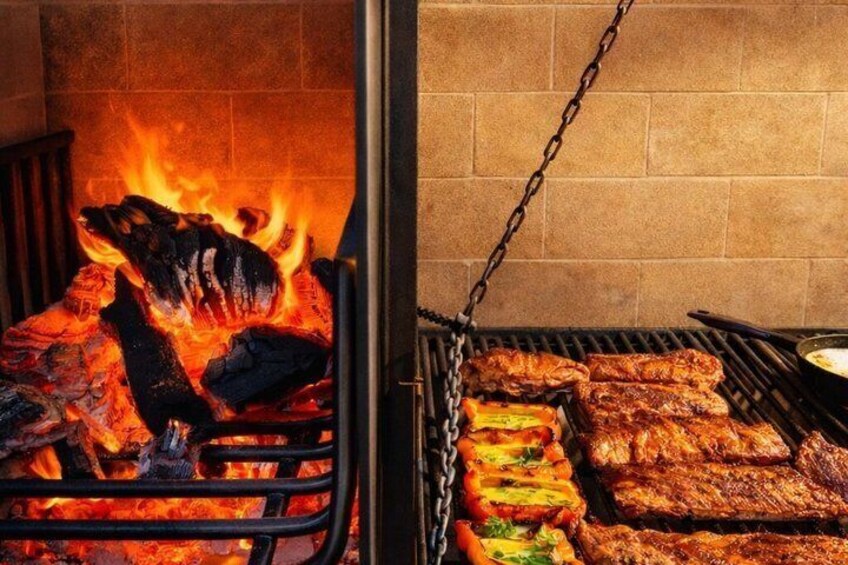 A grill with meat and vegetables being cooked over an open flame. 1
