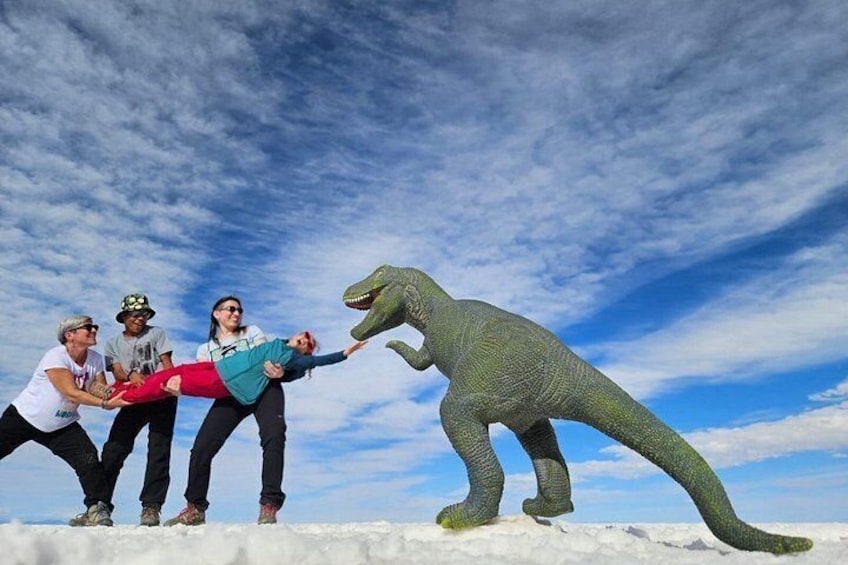 A group of people on a snowy surface with a large dinosaur model. 5