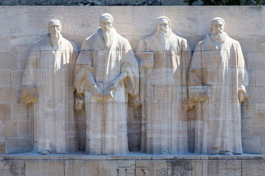 A stone monument with four statues of robed figures. 2